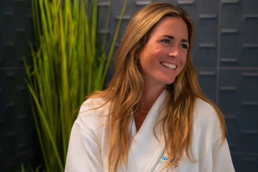 robed woman smiling and sipping champagne in spa room