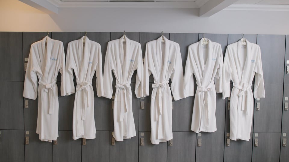six white robes hanging from lockers