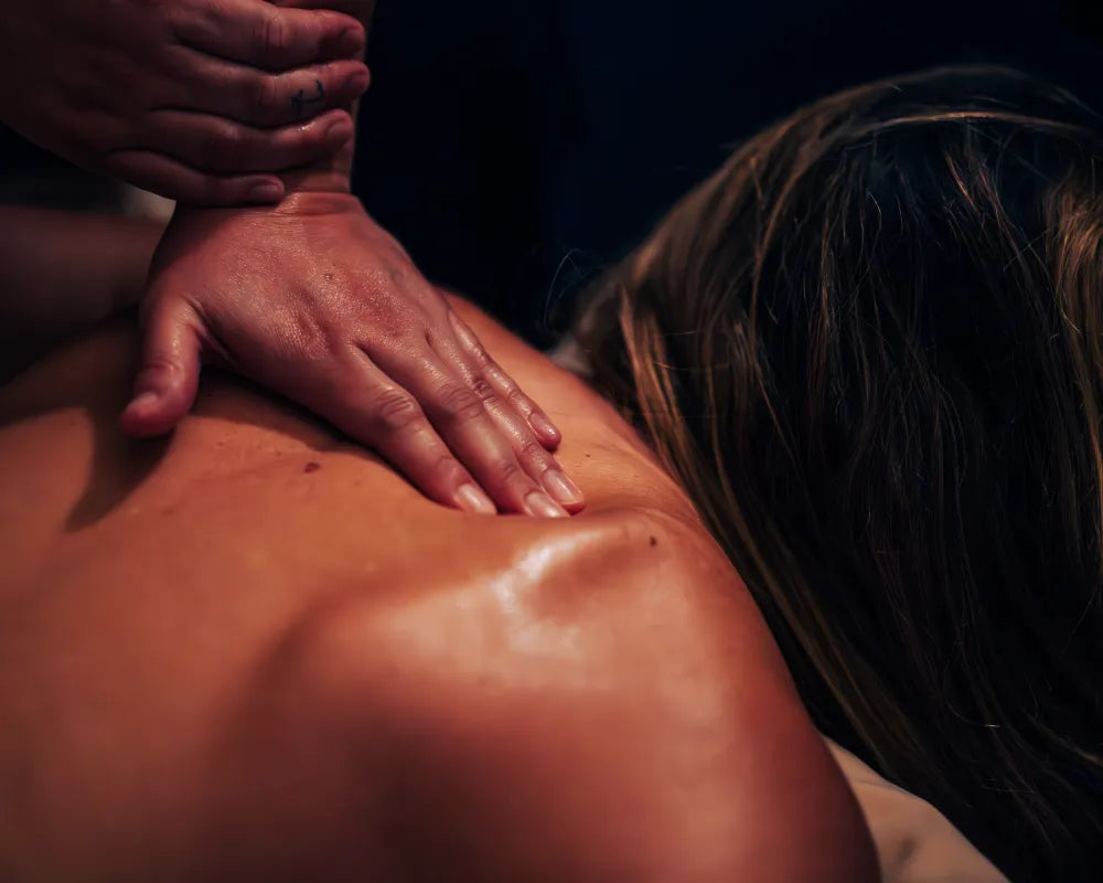 close-up of a person receiving a back massage with the masseuse’s hands pressing on their upper back