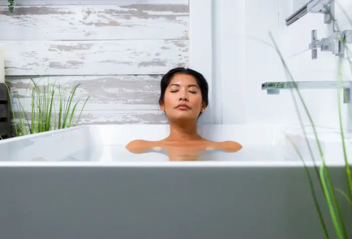 Woman relaxing in a modern bathtub with eyes closed.